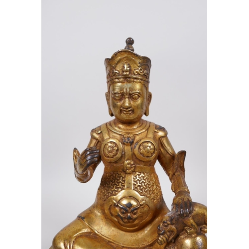 33 - A Tibetan gilt bronze of a deity seated on a lotus throne accompanied by a rat, 10