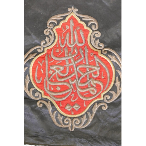 40 - An Islamic wall hanging embroidered with calligraphy in gilt metal wire on a red ground, 32