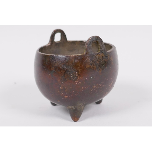 60 - A miniature Chinese bronze cauldron shaped censer with two loop handles and three cast feet, impress... 