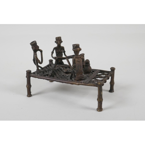 36 - An African benin bronze of figures sharing a meal, on a raised bed, 6