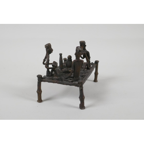 36 - An African benin bronze of figures sharing a meal, on a raised bed, 6