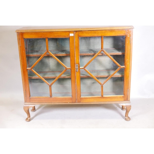 1142 - A 1930s golden walnut bookcase with two astragal glazed doors, raised on cabriole supports, 12