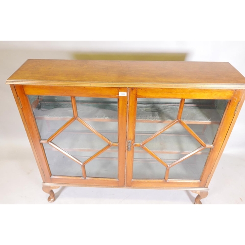 1142 - A 1930s golden walnut bookcase with two astragal glazed doors, raised on cabriole supports, 12