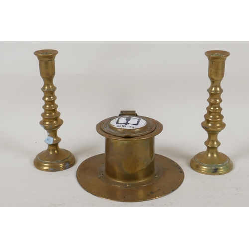 61 - An Art Deco brass capstan inkwell with enamelled cover and a pair of miniature brass candlesticks, 5... 