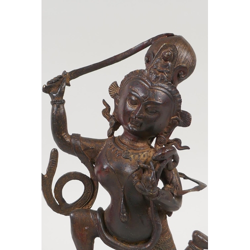 33 - A Tibetan bronze figure of a deity standing over a figure bearing a knife, with the remnants of gilt... 