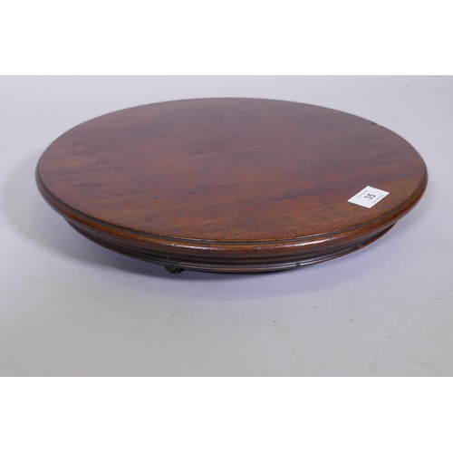 35 - A mahogany revolving table stand, fitted with three brass and leather castors, 15