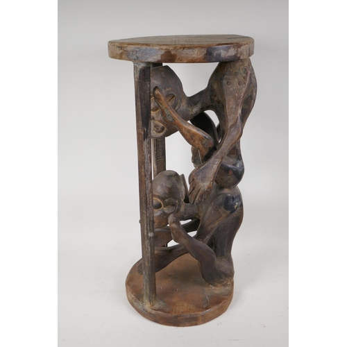 37 - An African hardwood stand, carved as two caged figures, 23½