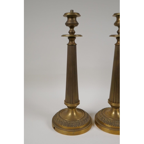 49 - A pair of bronze Empire style candlesticks in the form of fluted columns, part converted for electri... 