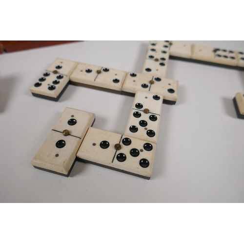 54 - An antique bone and ebony domino set with brass pins, in a fitted box