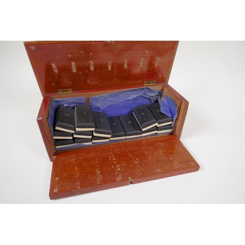 54 - An antique bone and ebony domino set with brass pins, in a fitted box