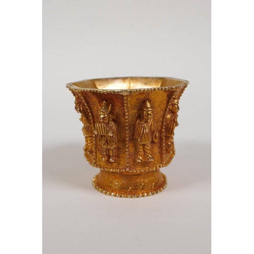 13 - A Chinese gilt metal libation cup of octagonal form, the eight sides with raised figural decoration,... 