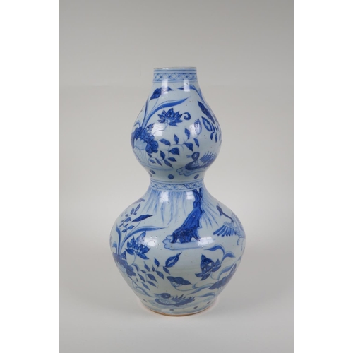 23 - A Chinese Ming style blue and white porcelain double gourd vase, with waterfowl and lotus flower dec... 