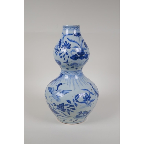 23 - A Chinese Ming style blue and white porcelain double gourd vase, with waterfowl and lotus flower dec... 