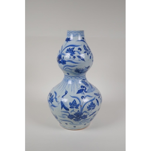 23 - A Chinese Ming style blue and white porcelain double gourd vase, with waterfowl and lotus flower dec... 