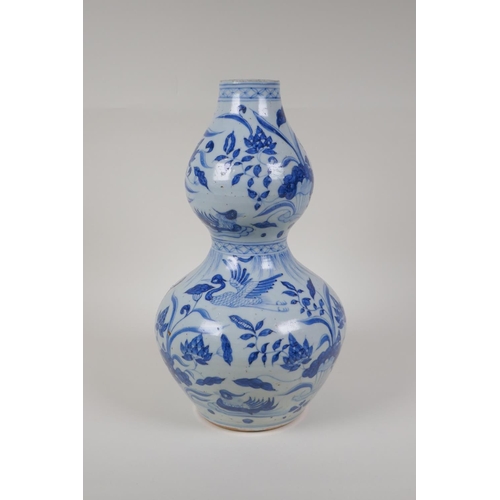 23 - A Chinese Ming style blue and white porcelain double gourd vase, with waterfowl and lotus flower dec... 