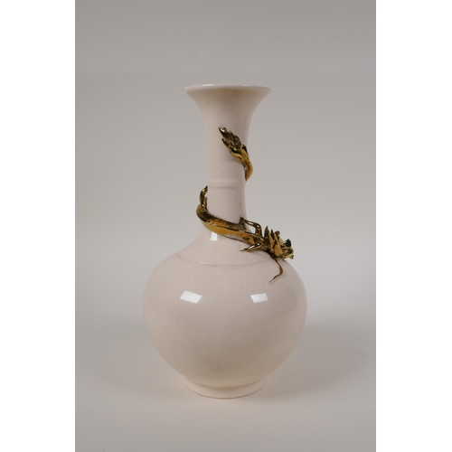 55 - A Chinese cream glazed porcelain bottle vase with applied and gilt dragon decoration to the neck, 10... 