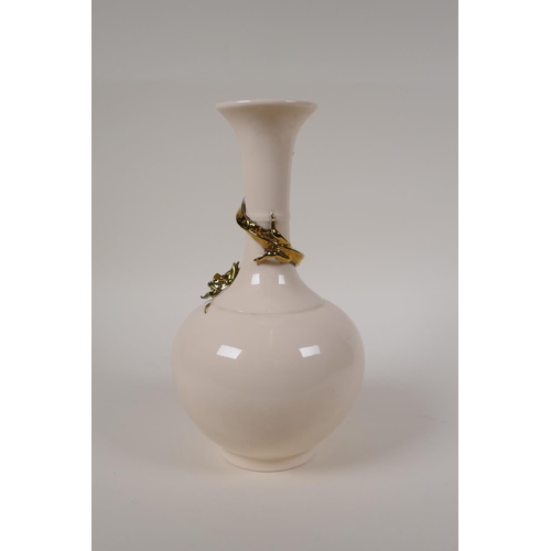 55 - A Chinese cream glazed porcelain bottle vase with applied and gilt dragon decoration to the neck, 10... 