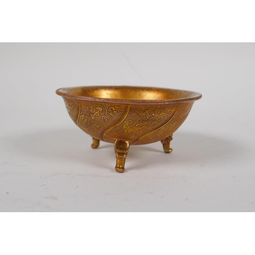 10 - A Chinese gilt metal cup with kylin, floral and bird decoration, raised on tripod supports, 3½... 