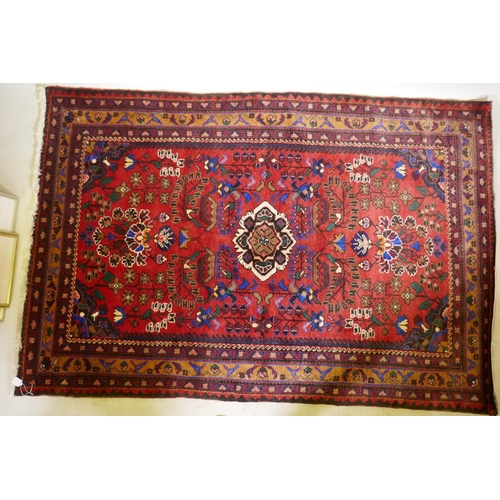 1213 - An oriental Hamadan wool carpet with medallion design on a red field, 82