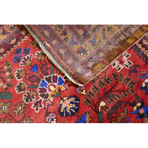 1213 - An oriental Hamadan wool carpet with medallion design on a red field, 82