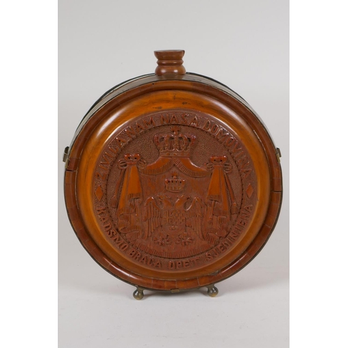 23 - A brass bound carved wood wine flask with coat of arms and fruiting vine decoration, 8½