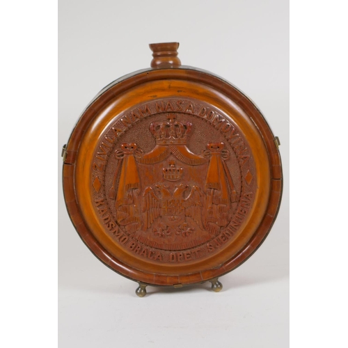 23 - A brass bound carved wood wine flask with coat of arms and fruiting vine decoration, 8½