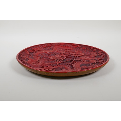 48 - A Chinese cinnabar lacquer style dish decorated with two dragons chasing the flaming pearl, characte... 