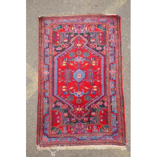 1170 - A Persian red ground wool rug with a multicolour geometric medallion design, 33