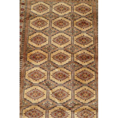 1188 - A gold ground wool Bokhara carpet, signed, 52