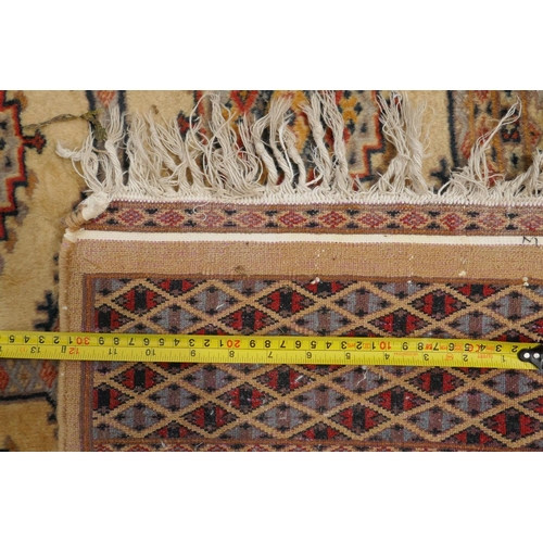 1188 - A gold ground wool Bokhara carpet, signed, 52