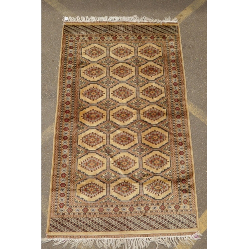 1188 - A gold ground wool Bokhara carpet, signed, 52