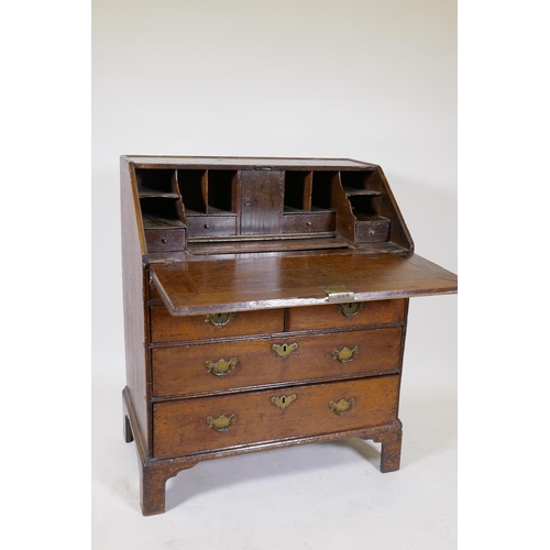 1169 - A Georgian oakfall front bureau with two short drawers over two long, the fall front opening to reve... 