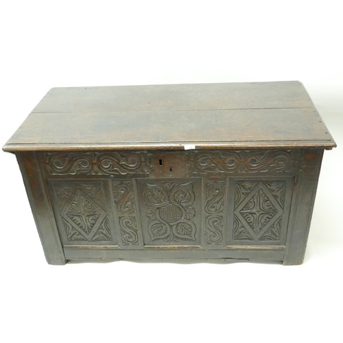 1202 - An C18th oak coffer with plank top and carved triple panel front, raised on stile supports, 49