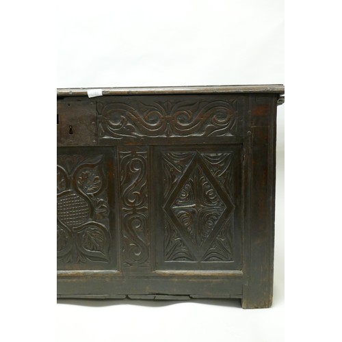 1202 - An C18th oak coffer with plank top and carved triple panel front, raised on stile supports, 49