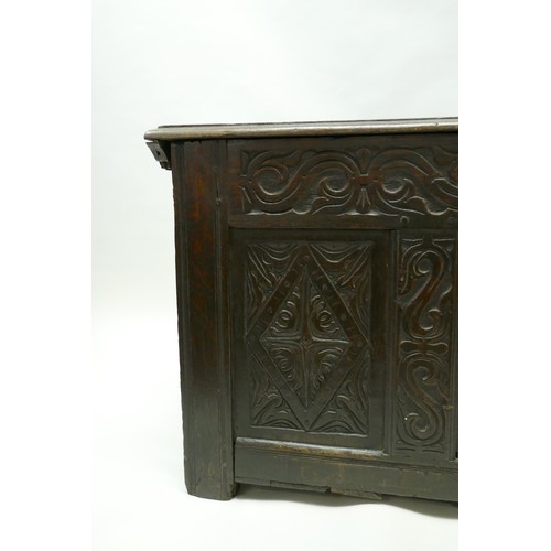 1202 - An C18th oak coffer with plank top and carved triple panel front, raised on stile supports, 49