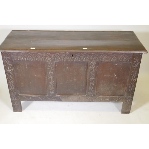 1183 - An C18th oak coffer with triple panel front and carved decoration, raised on stile supports, 54