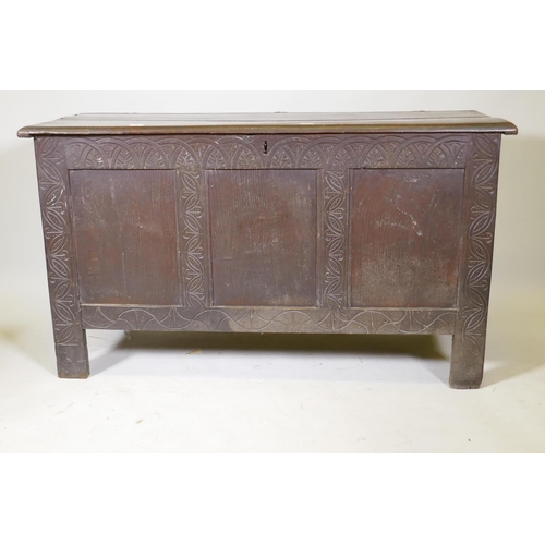 1183 - An C18th oak coffer with triple panel front and carved decoration, raised on stile supports, 54