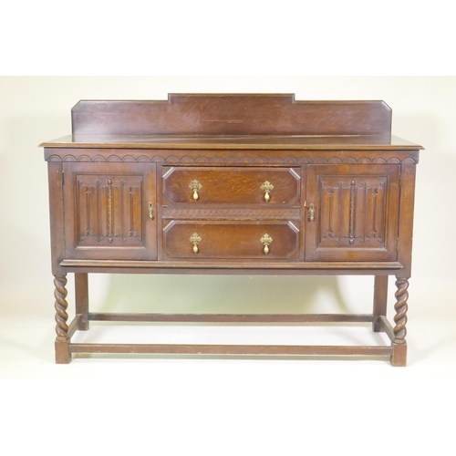 1203 - A 1930s Jacobean style oak buffet, two cupboards with linen fold carved decoration flanking two draw... 