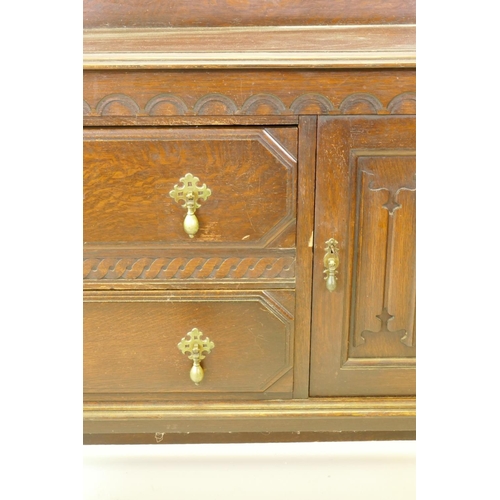 1203 - A 1930s Jacobean style oak buffet, two cupboards with linen fold carved decoration flanking two draw... 