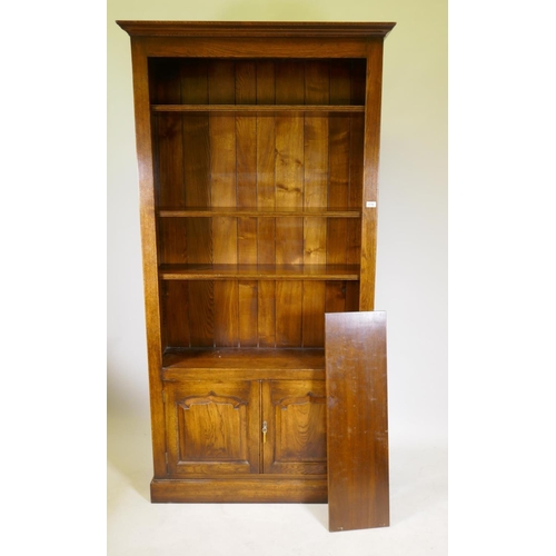 1167 - An oak open bookcase over two cupboard doors, 41½