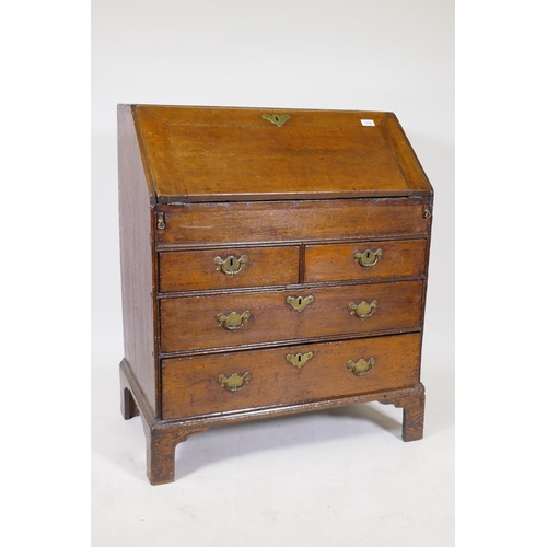 1169 - A Georgian oakfall front bureau with two short drawers over two long, the fall front opening to reve... 