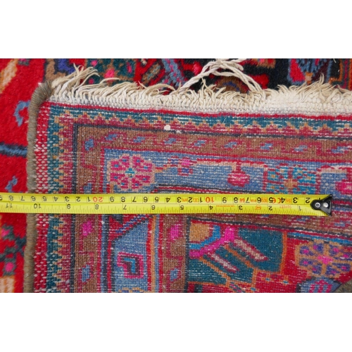 1170 - A Persian red ground wool rug with a multicolour geometric medallion design, 33