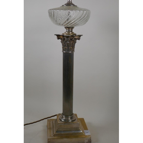 12 - A Victorian silver plated Corinthian column table lamp with glass reservoir, converted to electricit... 