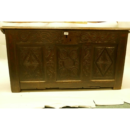 1202 - An C18th oak coffer with plank top and carved triple panel front, raised on stile supports, 49