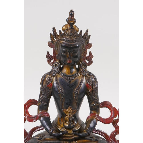 71 - A Sino Tibetan bronze figure of Buddha with gilt and coppered patina, 21cm high