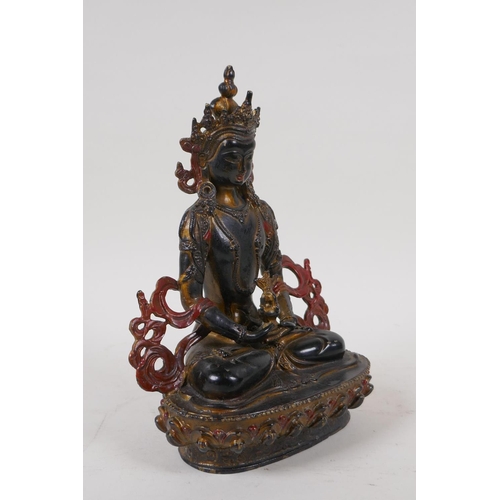 71 - A Sino Tibetan bronze figure of Buddha with gilt and coppered patina, 21cm high