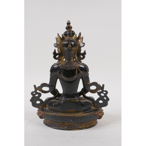 71 - A Sino Tibetan bronze figure of Buddha with gilt and coppered patina, 21cm high