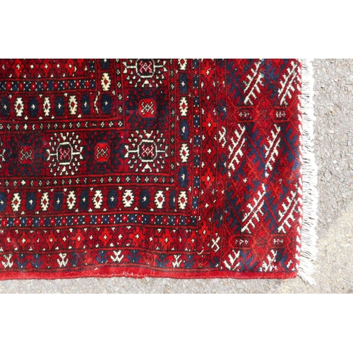 1176 - A deep red ground Persian Bokhara carpet, 184cm x 280cm