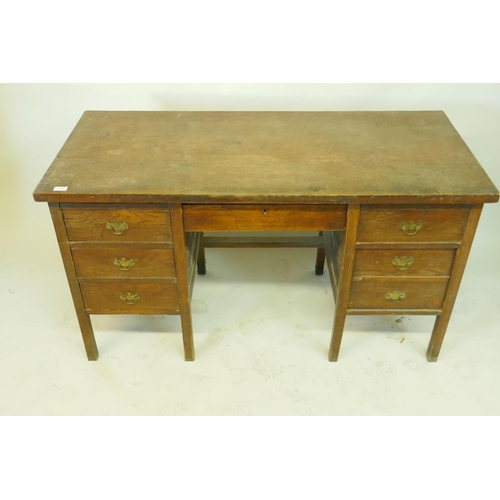 1199 - An oak office desk of five drawers, raised on square supports, early C20th, 138 x 62 x 77cms