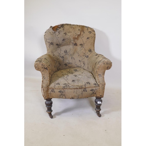 1200 - A Victorian easy chair with shaped back and scroll arms, raised on turned supports with brass castor... 